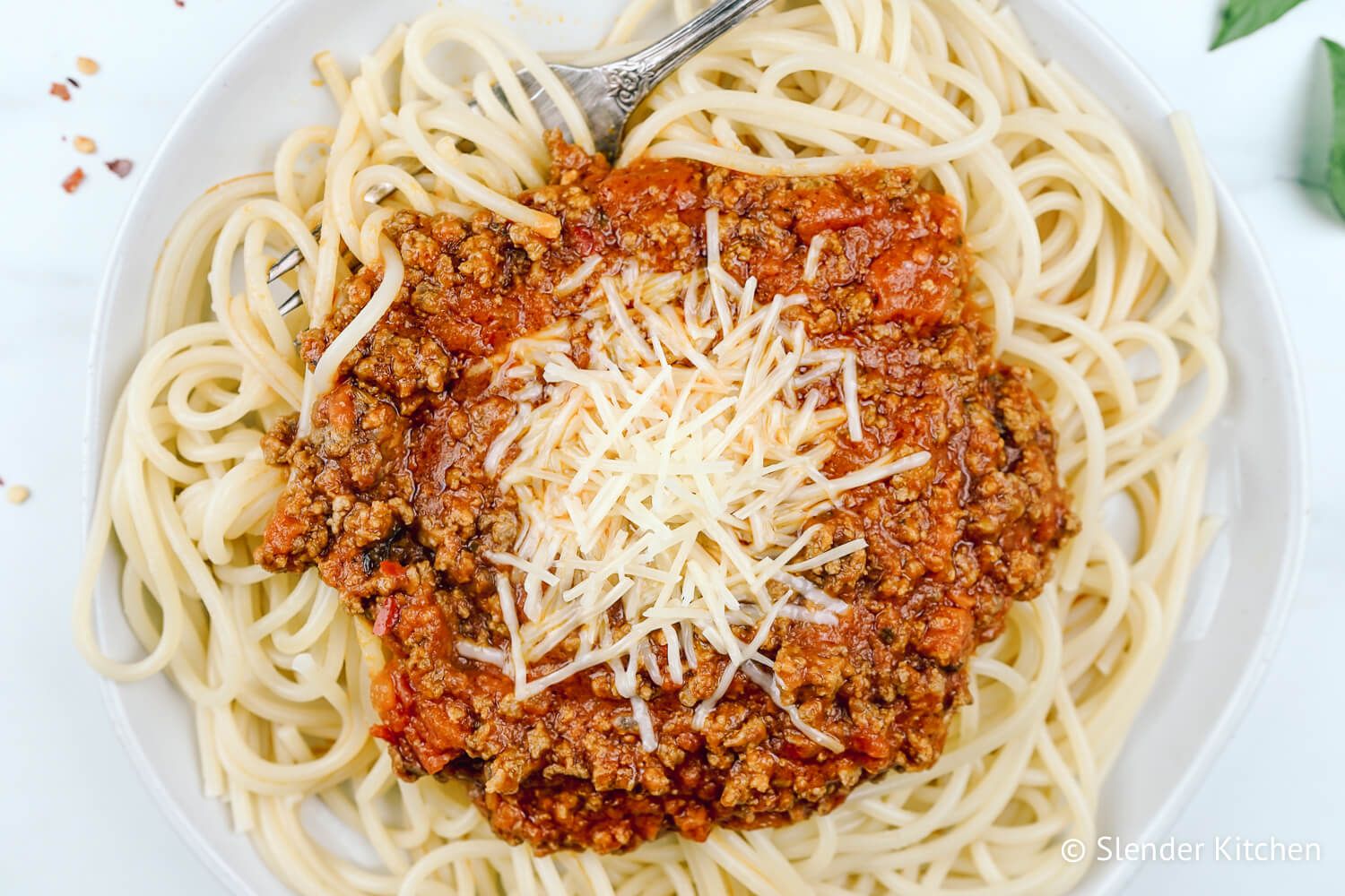 Arrabiata sauce with pasta on a plate with red pepper flakes and cheese.