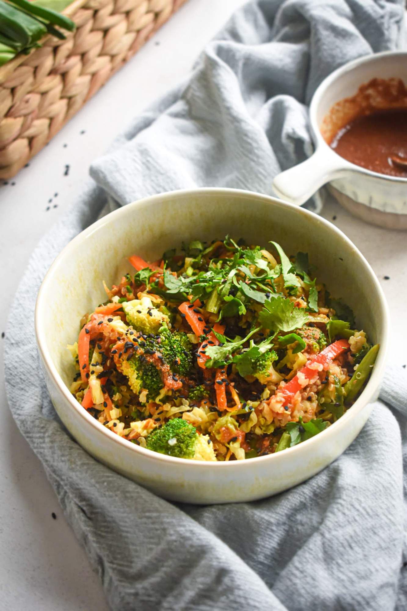 Asian stir fry with quinoa, broccoli, cabbage, and carrots in a spicy stir fry sauce in a bowl. 