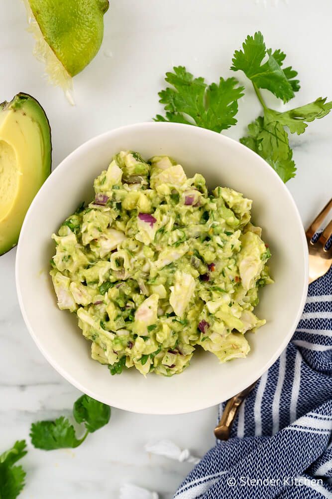 Avocado chicken salad with cilantro, lime juice, red onion, and shredded chicken in a bowl.