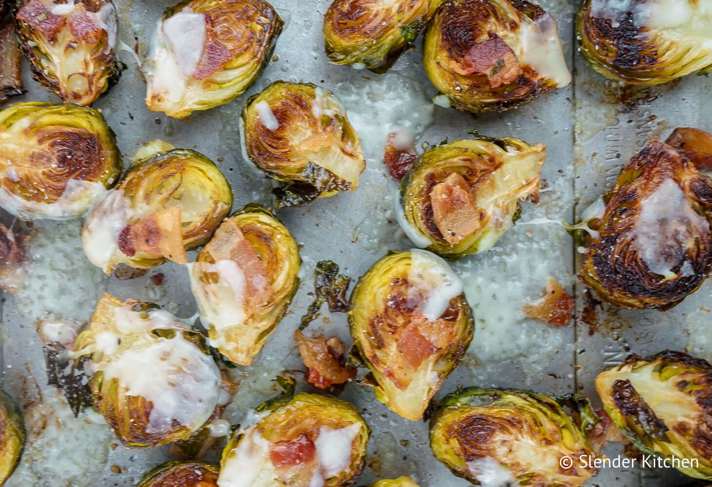 Brussel sprouts and bacon with garlic and cheese on a baking sheet.