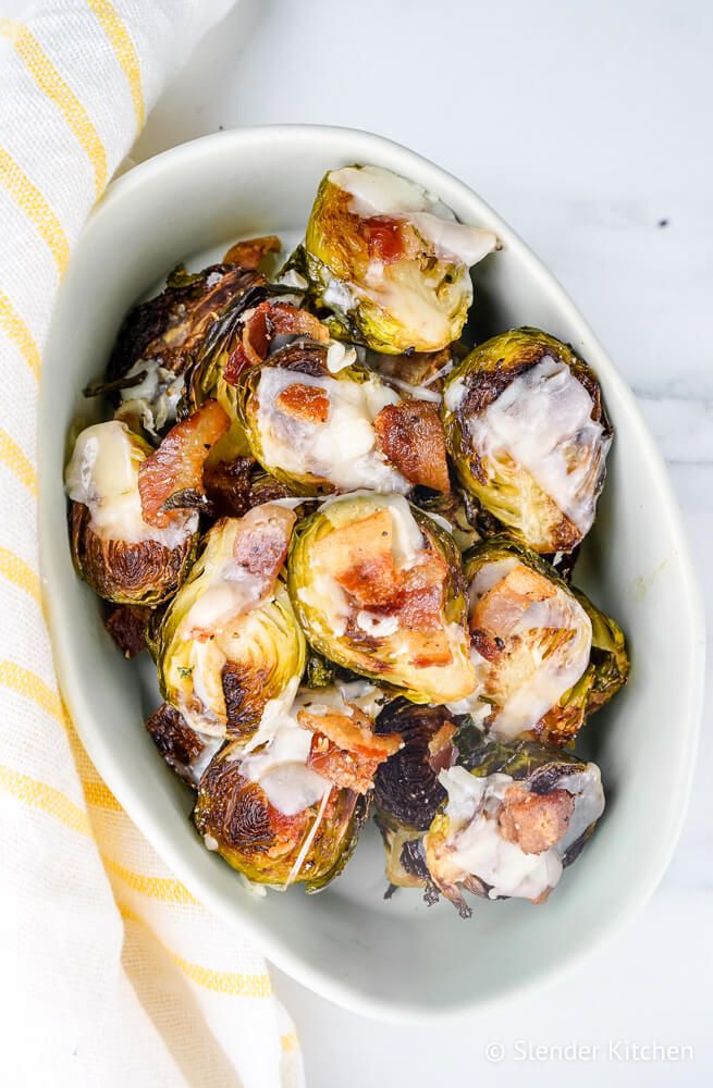 Bacon garlic Brussel sprouts in a small white bowl with melted Parmesan cheese.