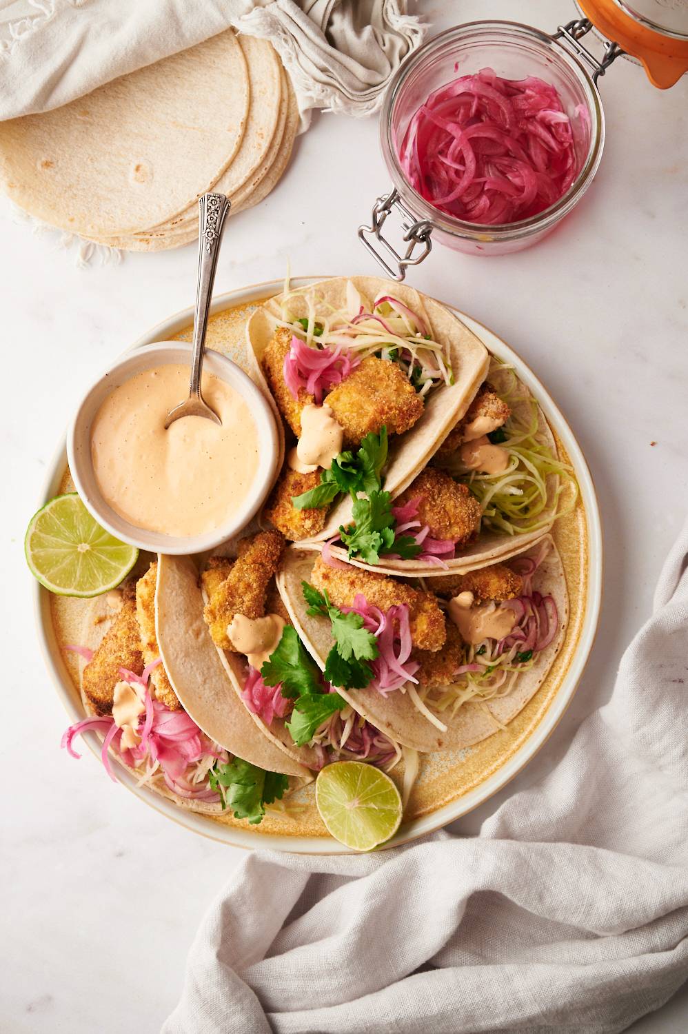 Baked baja fish tacos with coleslaw, pickled red onions, and creamy fish taco sauce served in corn tortillas.