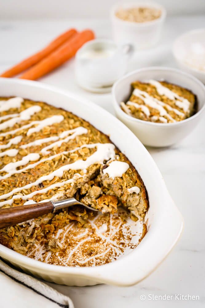 Carrot oatmeal baked in a dish with shredded carrots, raisins, oats, coconut, and a cream cheese glaze.