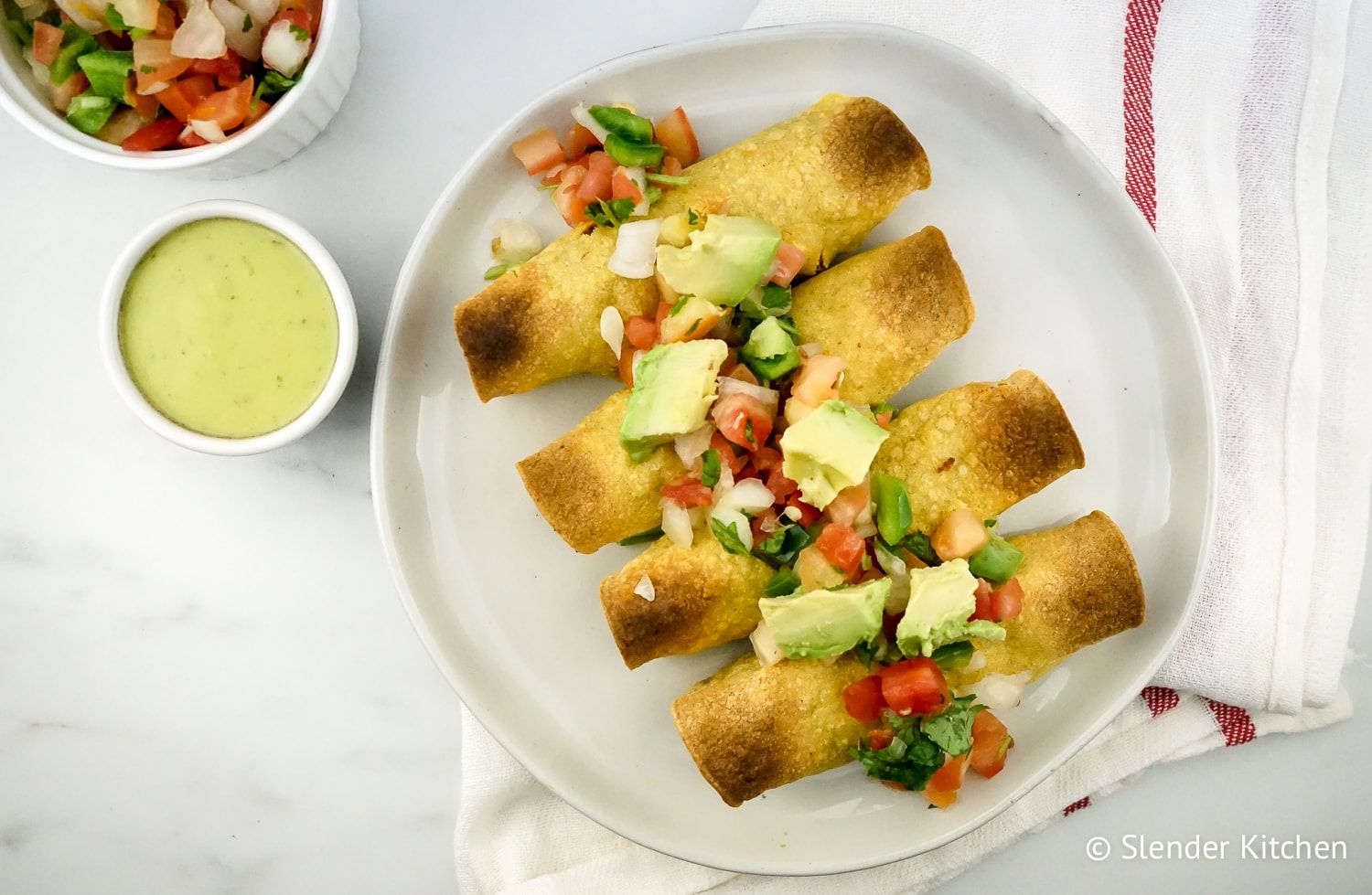 Baked Chicken and Bean Taquitos topped with tomatoes and avocado