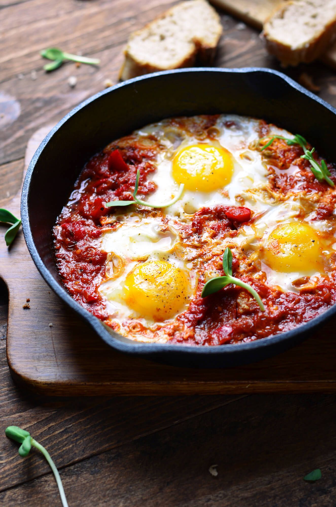 Baked eggs in a skillet with fresh basil and Parmesan cheese.