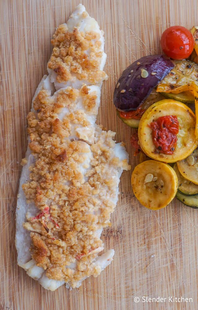 Baked haddock recipe with seafood stuffing on top and vegetables on the side.