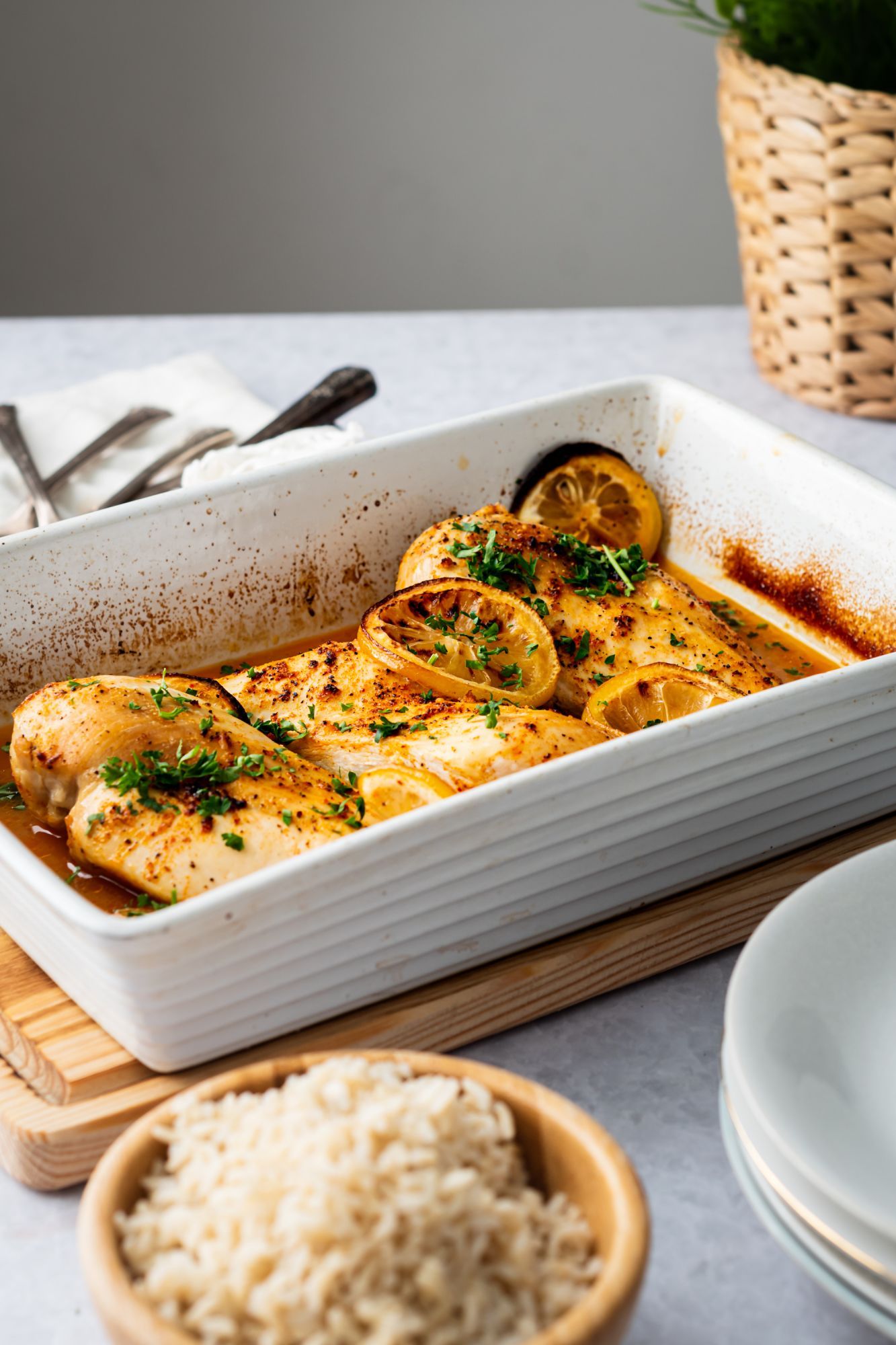 Lemon pepper chicken breasts in a baking dish with brown rice on the side.