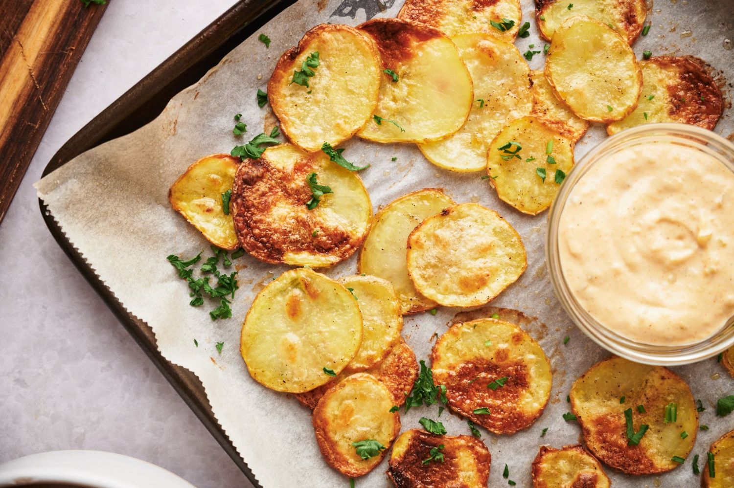 Potato chips that are baked in the oven on a baking sheet with dipping sauce.