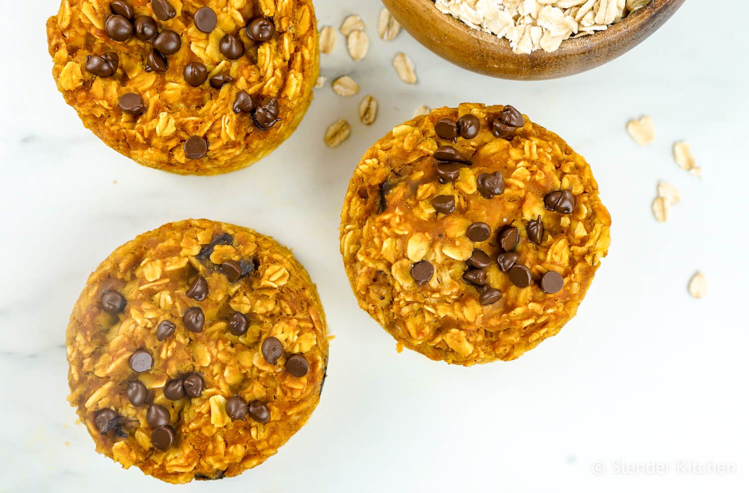 Pumpkin oatmeal with chocolate chips and loose oats on a white board.