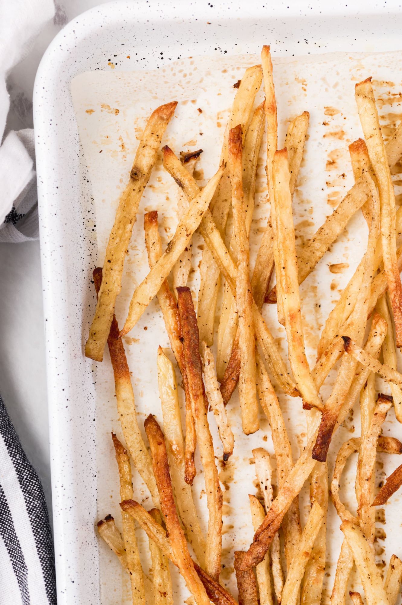 Healthy baked skinny fries on a baking sheet with parchment paper.