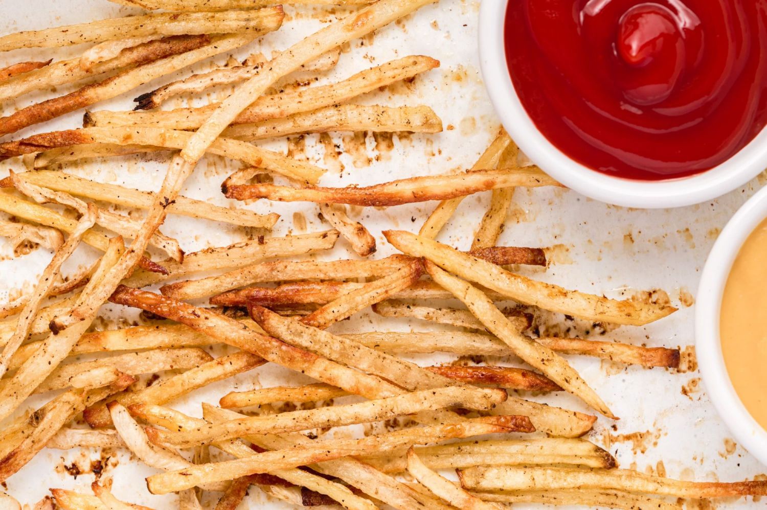 Crispy thinly sliced potato and turnip fries on a baking sheet with crispy browned edges.