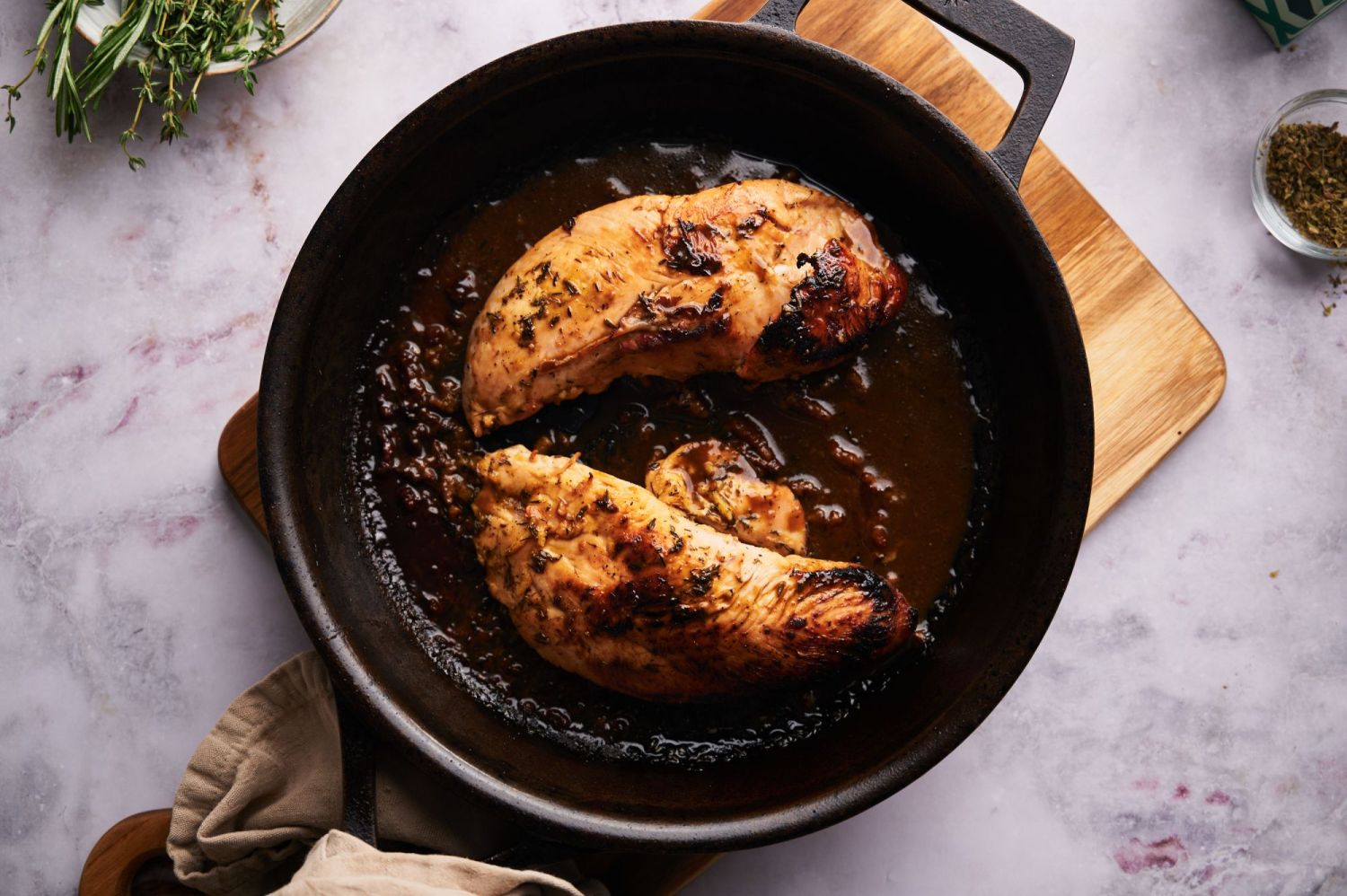 Marinated baked turkey tenderloins in a cast iron skillet with mustard sauce and fresh herbs.