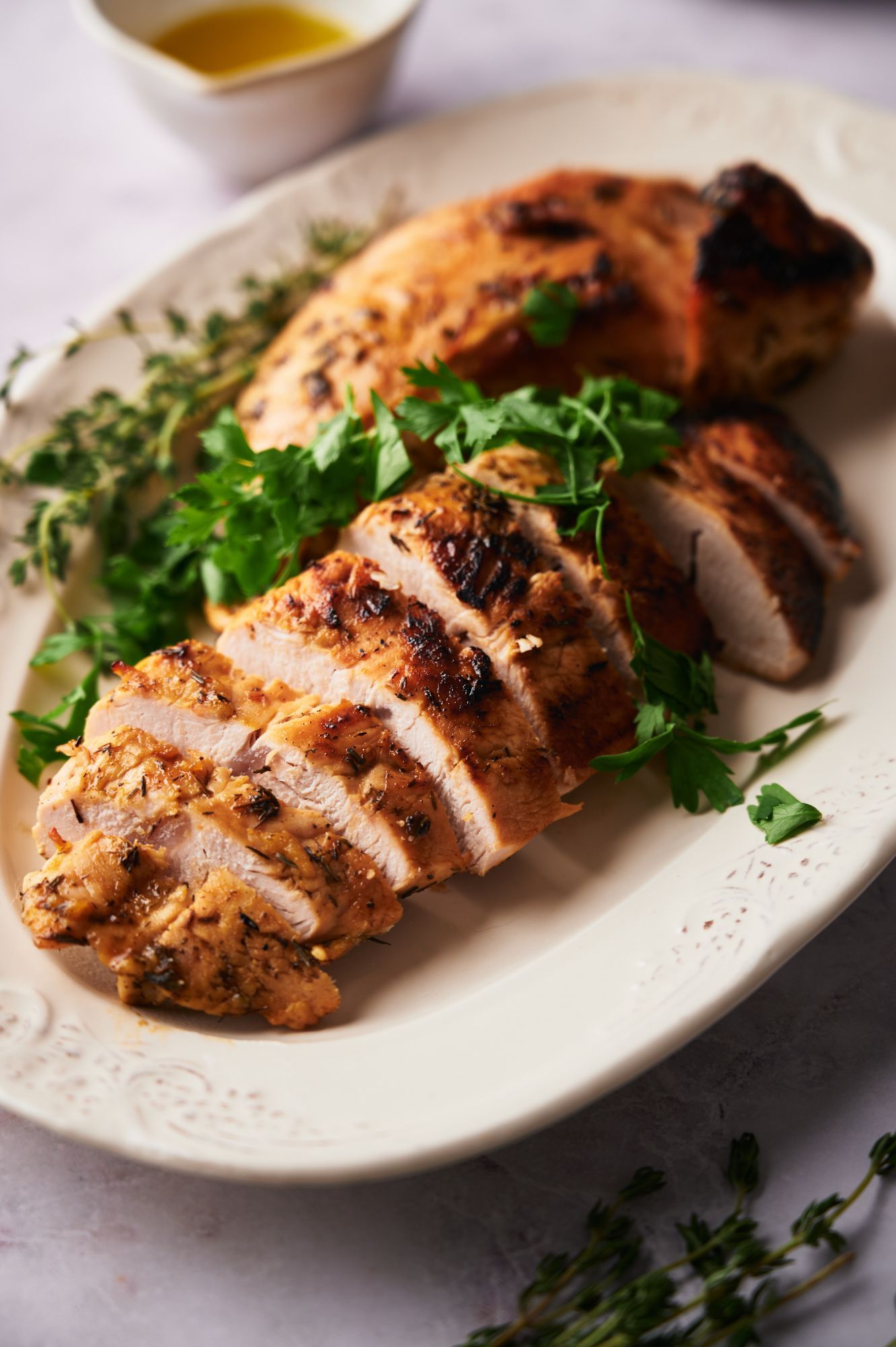 Baked turkey breast tenderloin with maple mustard marinade on a plate with fresh parsley.