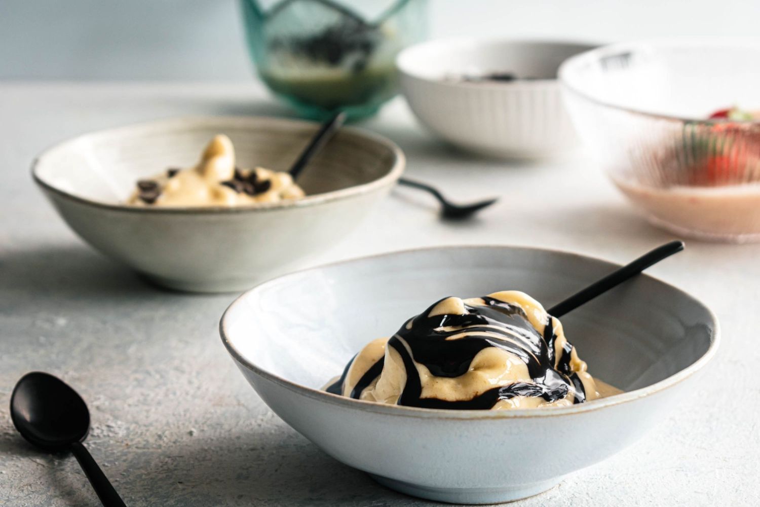 Fruit ice cream made with frozen bananas and served in a bowl with chocolate sauce.