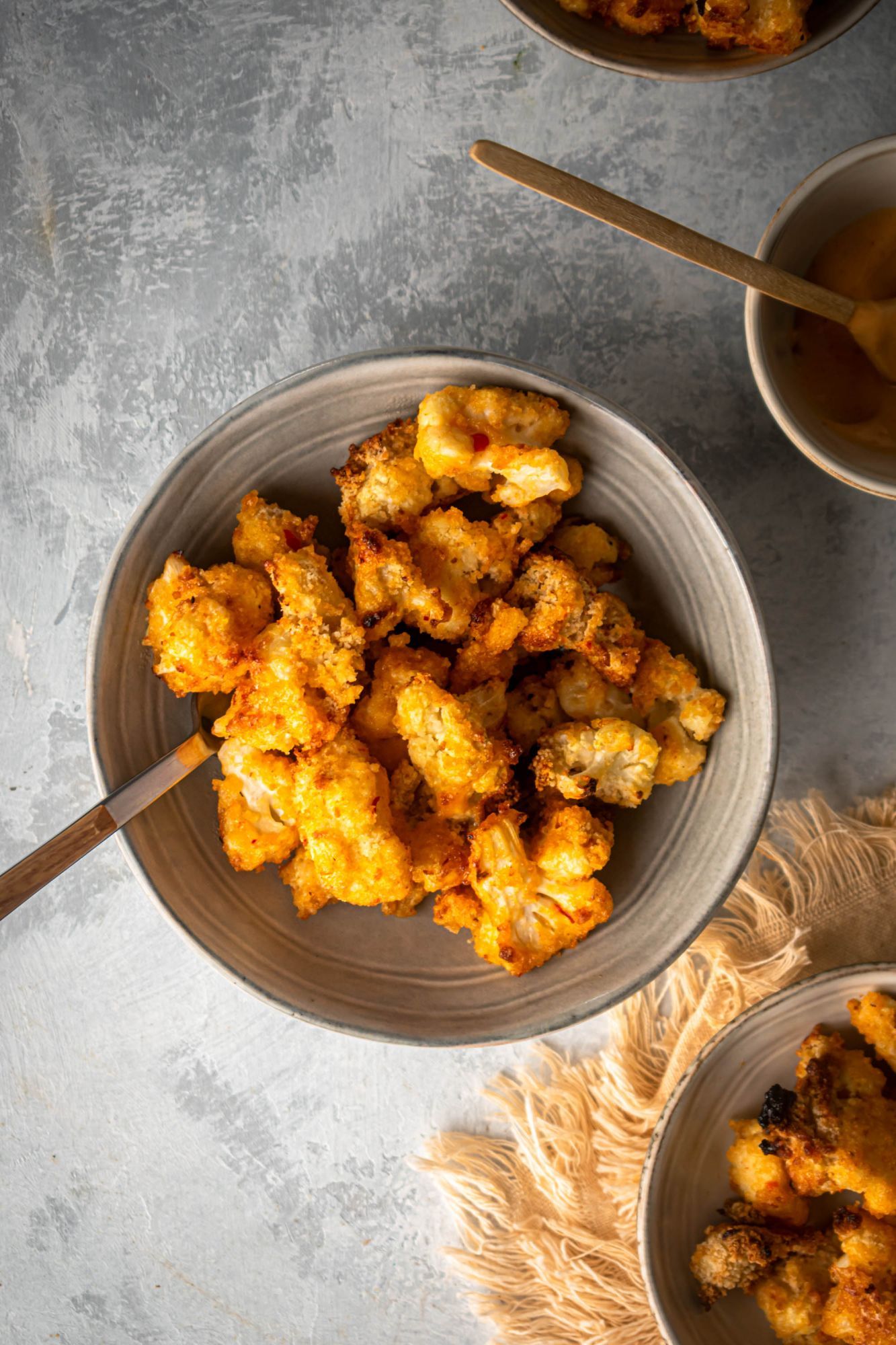 Crispy bang bang cauliflower on a plate with a creamy Sriracha and sweet chili sauce.