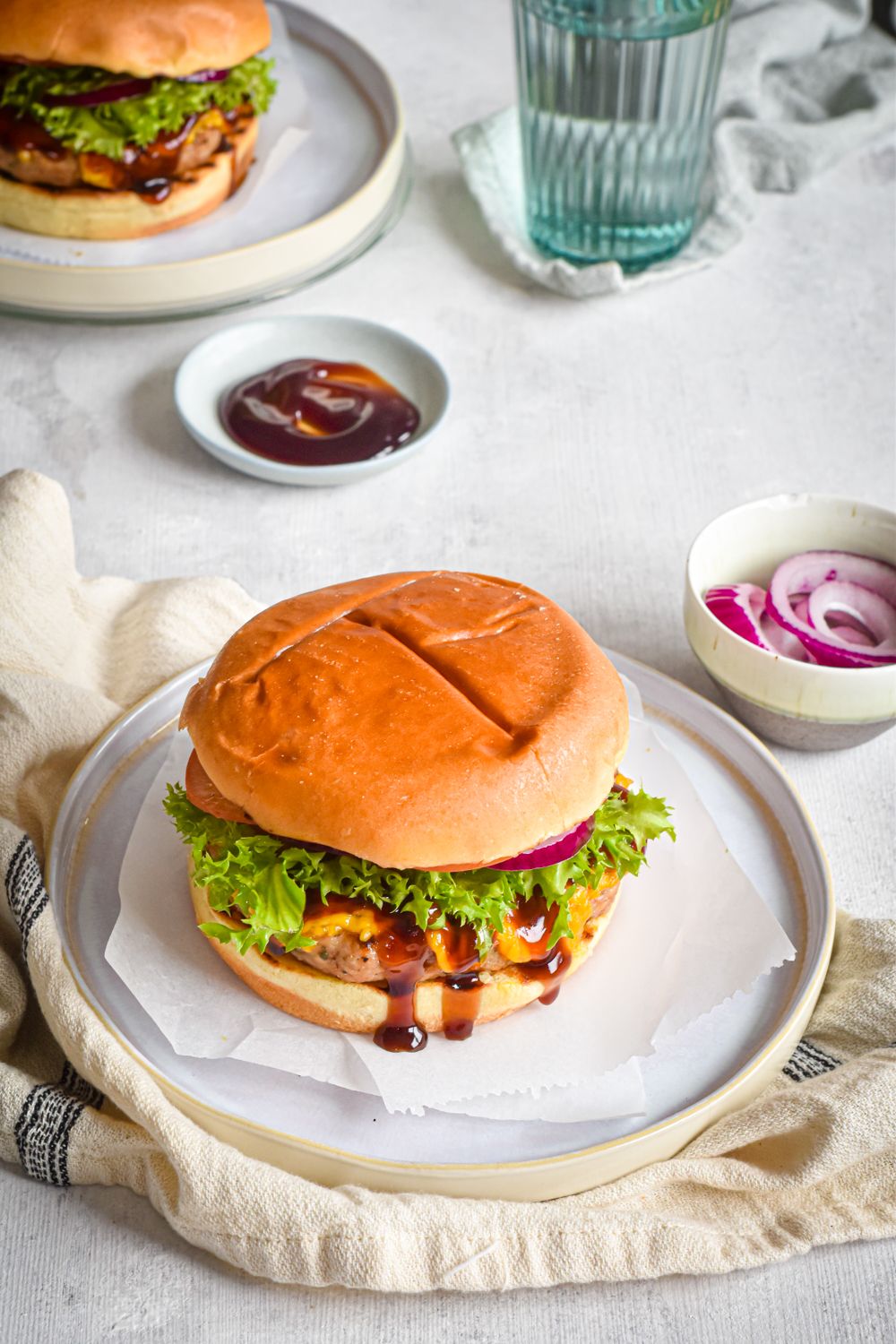 Turkey burgers with barbecue and cheddar cheese on a roll with lettuce, tomato, and onion.