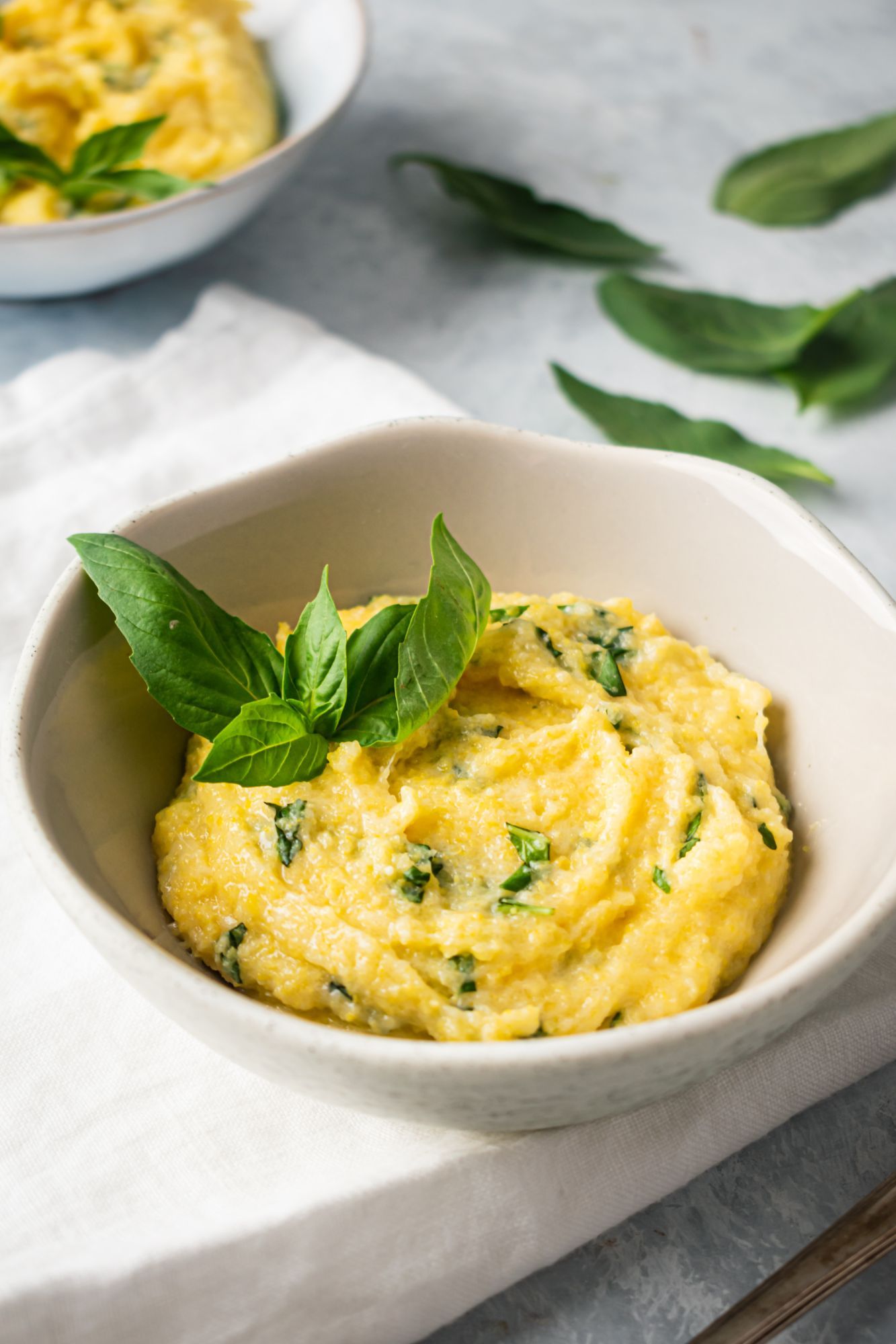 Creamy Parmesan polenta with fresh basil served in two bowls.