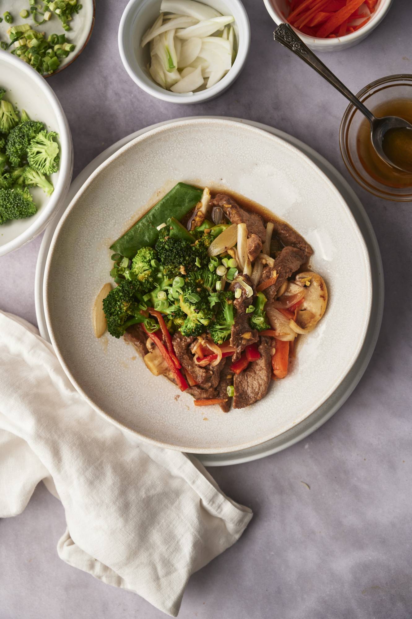 Stir fried beef and vegetables served in a white bowl with green onions.