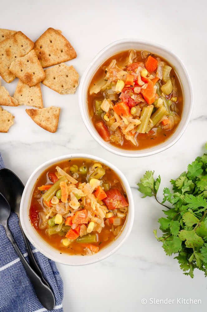 Easy Vegetable soup in two bowls with crackers and cilantro on the side.