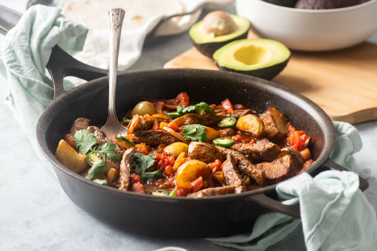 Skillet with bistec ranchero served with tomatoes, peppers, potatoes, cilantro, and sliced jalapenos.