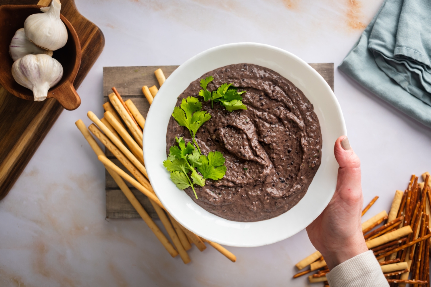 Creamy black bean hummus in a white bowl with cilantro leaves.