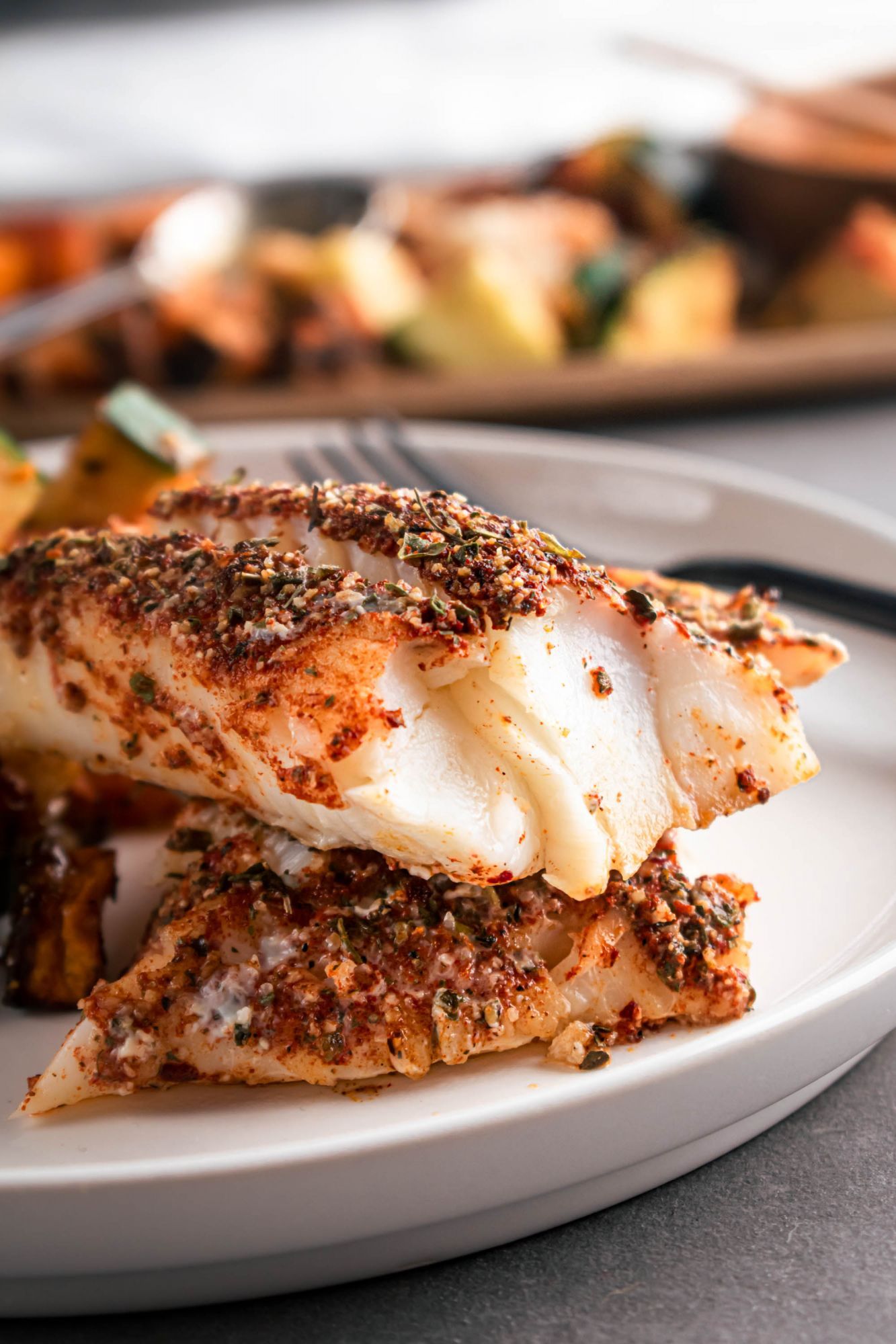 Baked blackened cod with homemade seasoning served with sweet potatoes and zucchini.