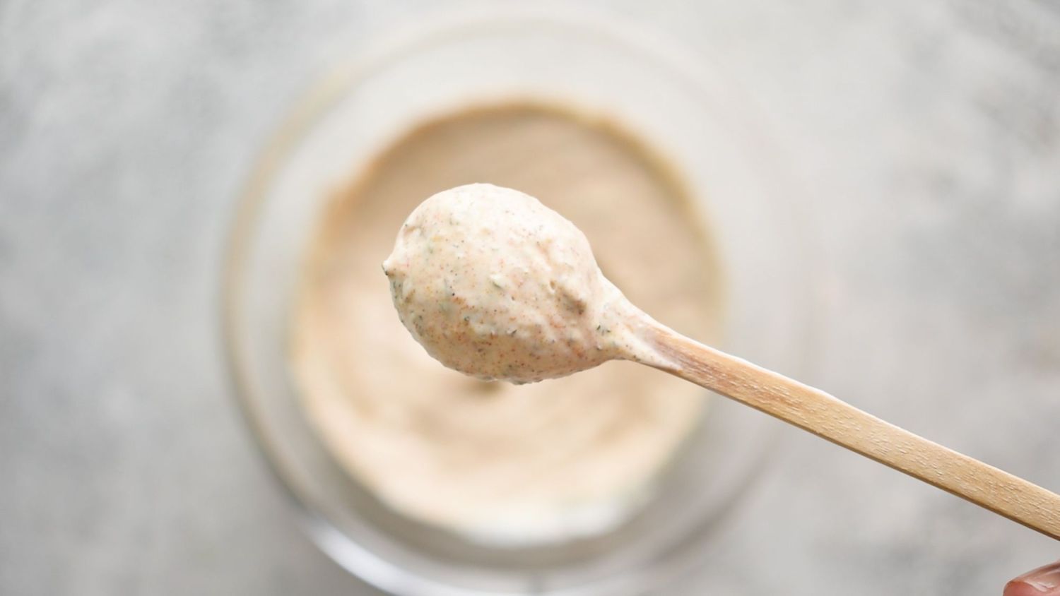 Spoonful of blackened ranch dressing with herbs and spices on a wooden spoon.