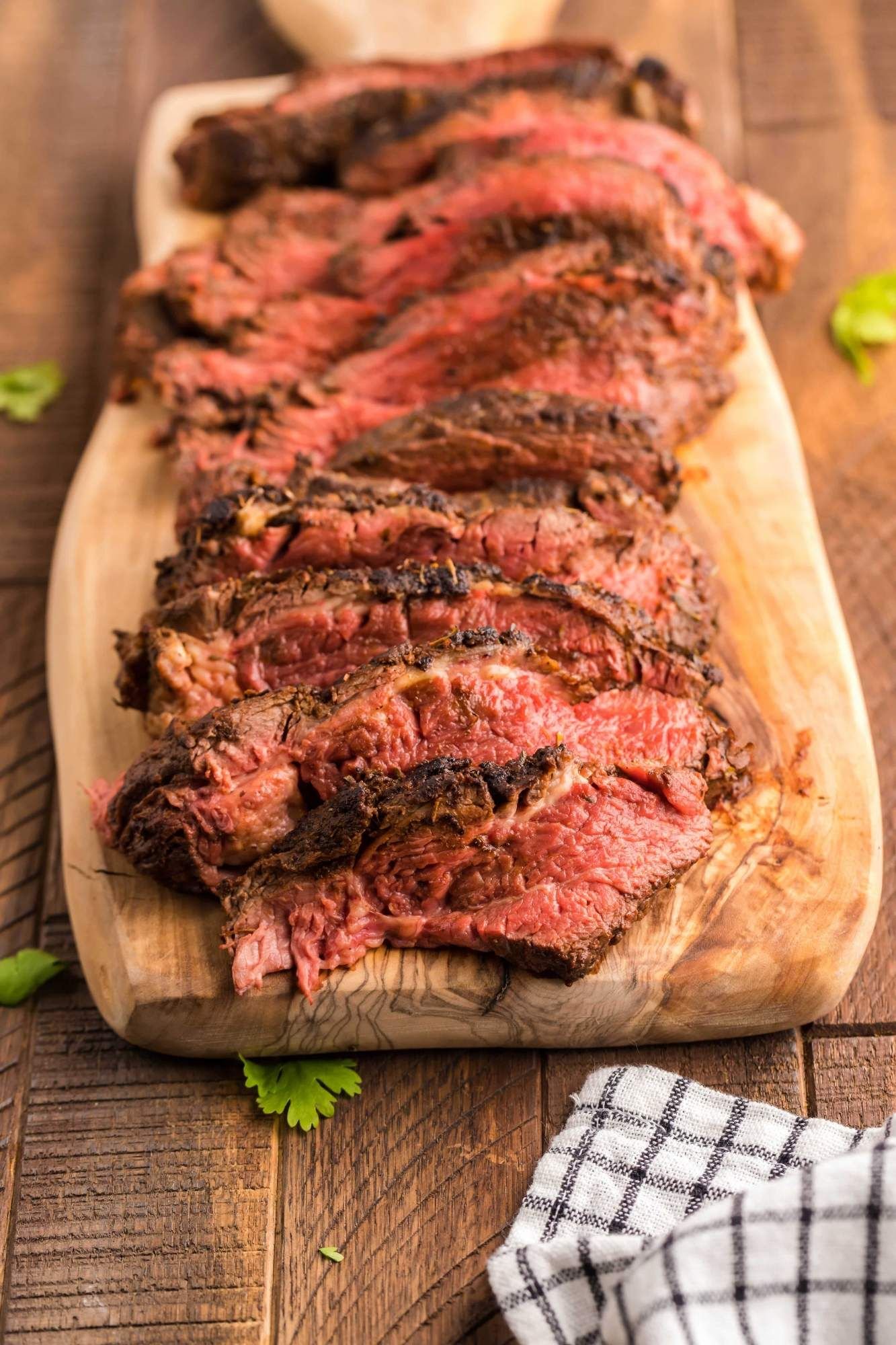 Steak with blackening seasoning coked medium rare and sliced on a cutting board.