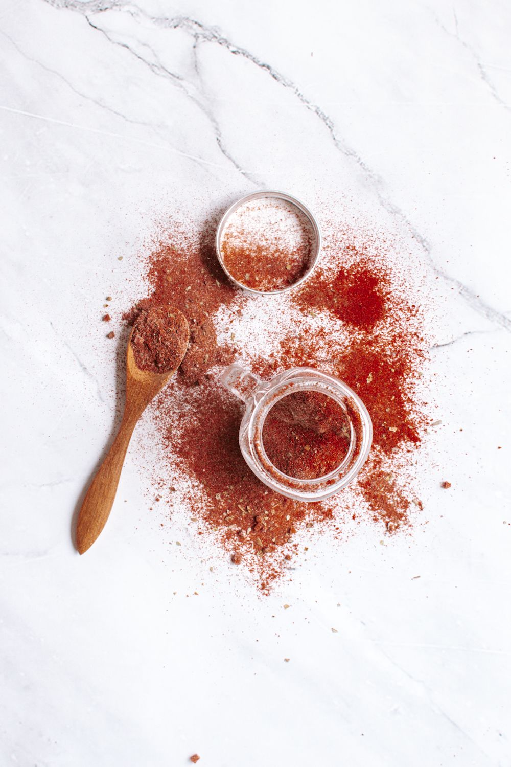 Blackening spices in a small glass jar with a gold spoon on the side.