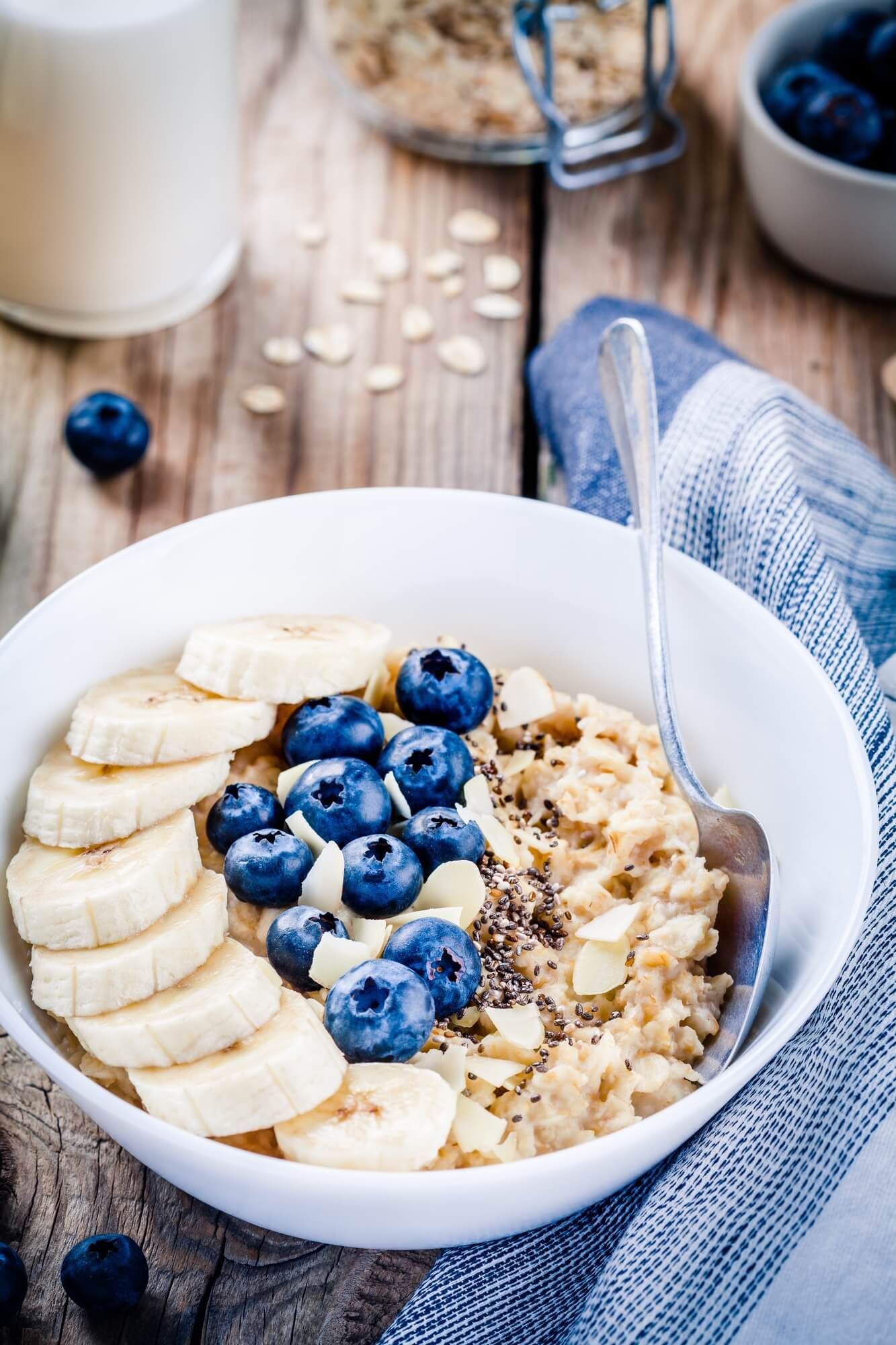 Chai Overnight oats with blueberries and bananas in a bowl with spoon.