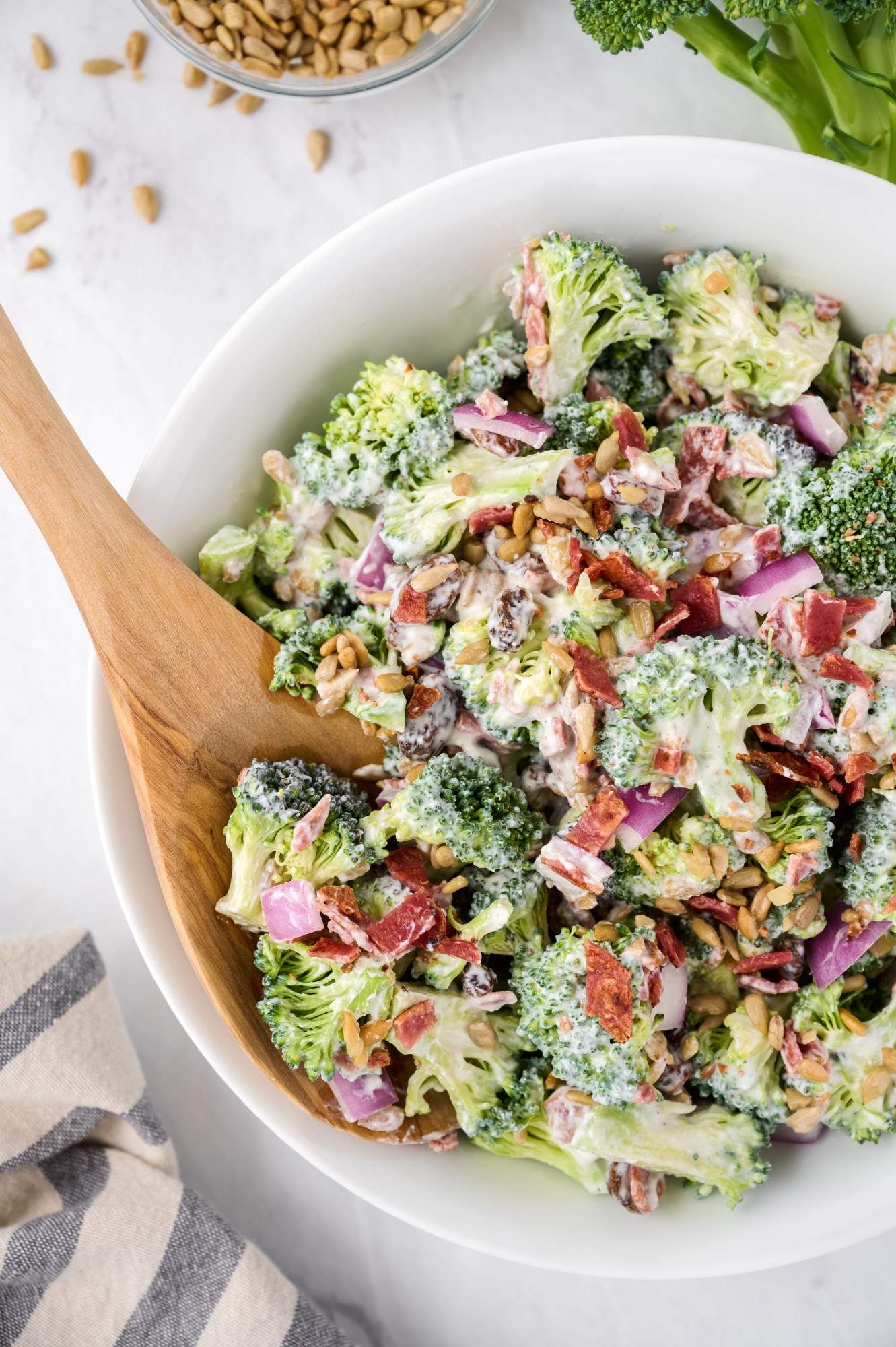 Healthy broccoli salad made with a creamy yogurt dressing in a bowl with sunflower seeds, red onion, and turkey bacon.