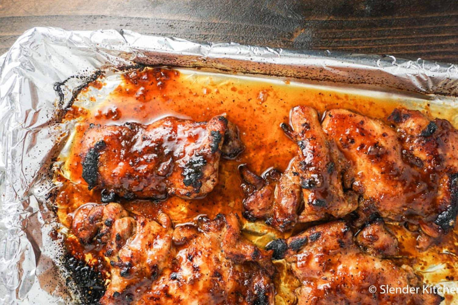 Broiled Chicken thighs in Asian sauce on a sheet pan with foil.