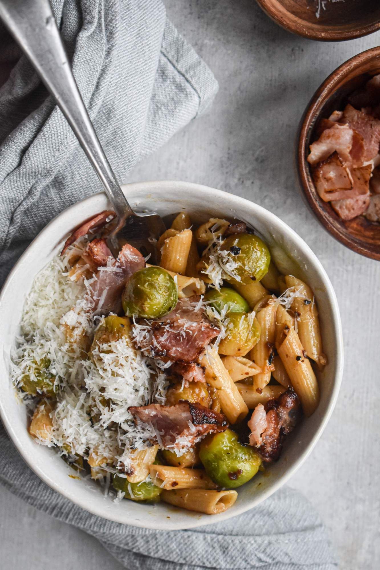 Pasta with brussels sprouts and bacon topped with lemon juice and Parmesan cheese.