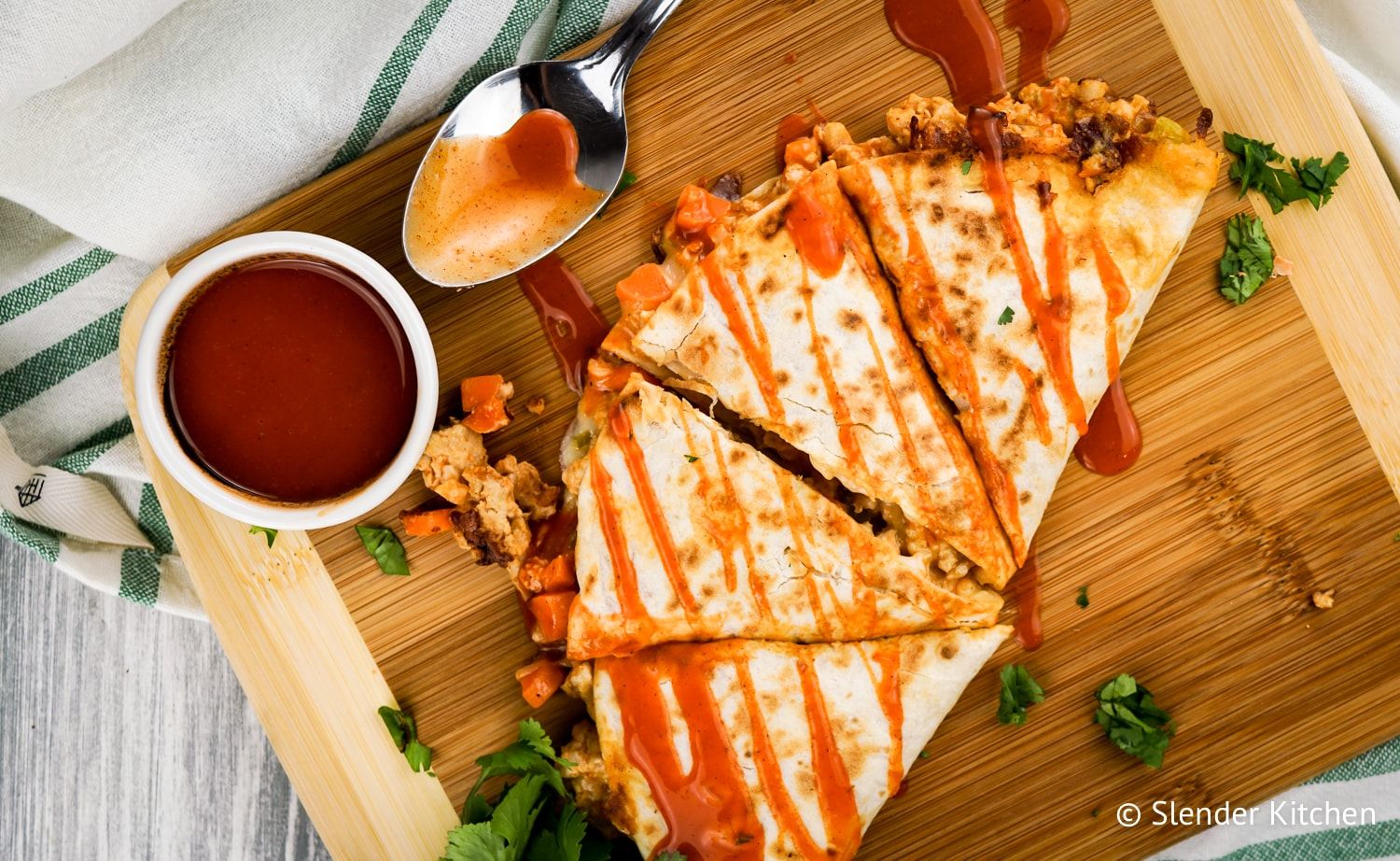 Healthy Buffalo Chicken Quesadilla cut into four pieces with extra sauce.