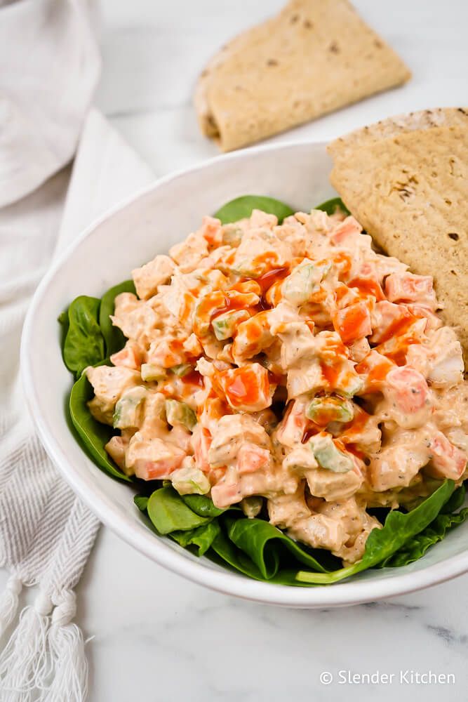 Buffalo chicken salad with Greek yogurt in a bowl with spinach and a wrap.