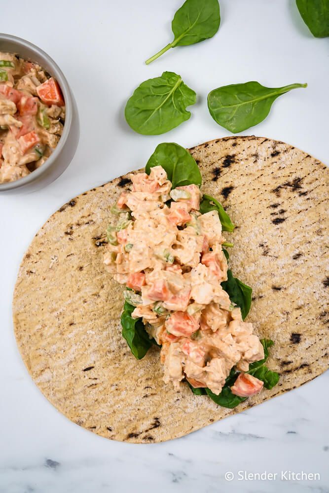 Ranch buffalo chicken salad wrap in a tortilla with spinach, buffalo chicken salad, carrots, and celery.