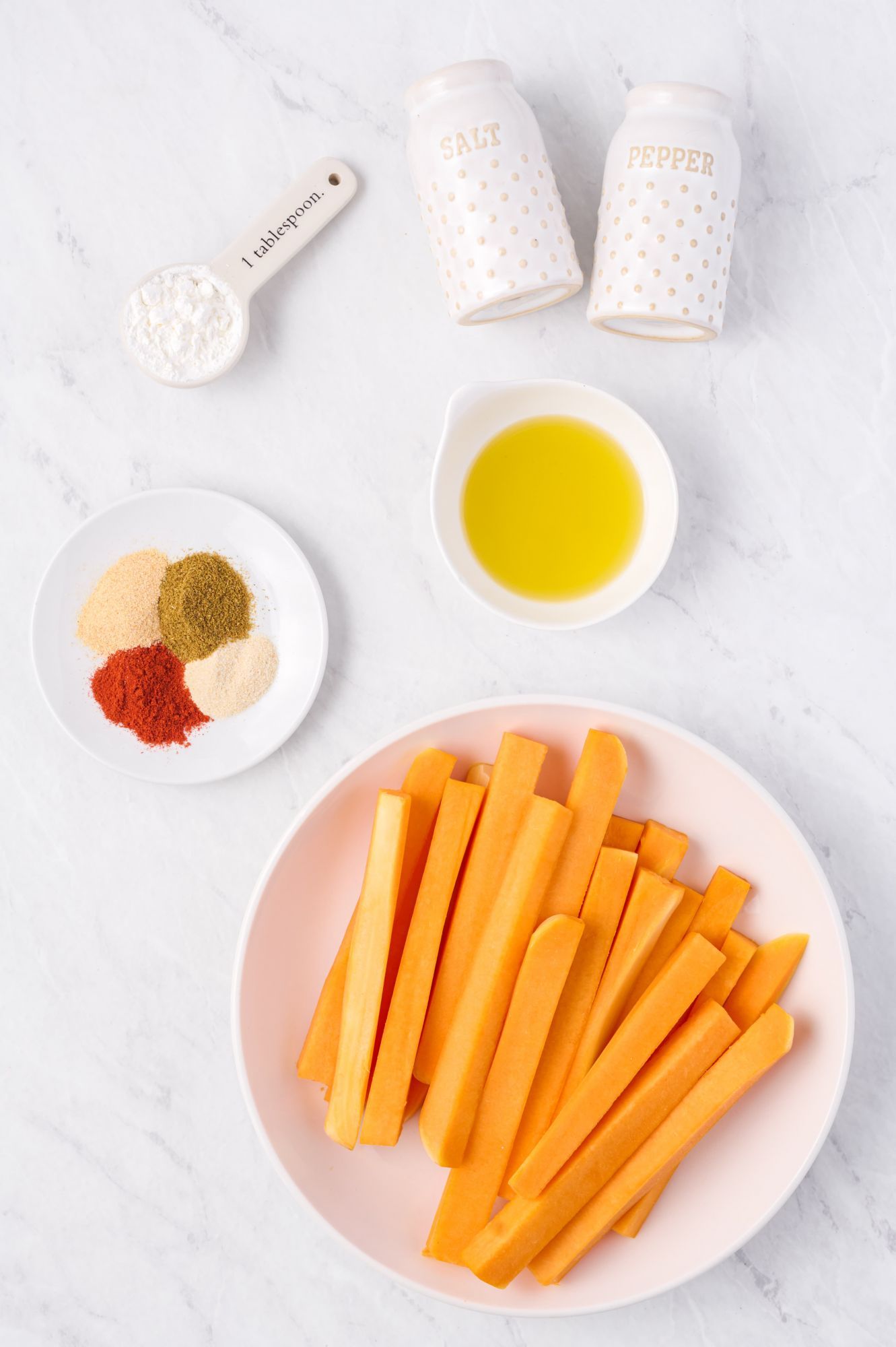 Ingredients for butternut squash fries including sliced butternut squash, olive oil, spices, and cornstarch.