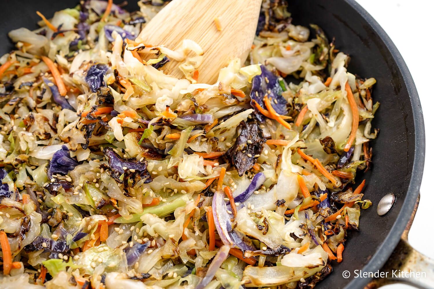 Stir fry cabbage in a skillet with sesame seeds.