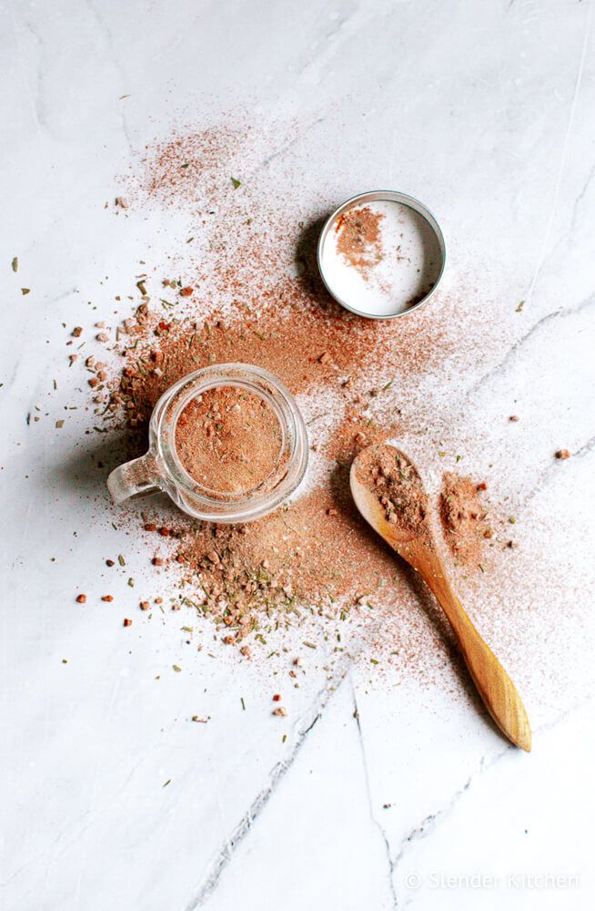 Cajun spice blend with paprika, oregano, thyme, and more in a jar and spilled on the side.