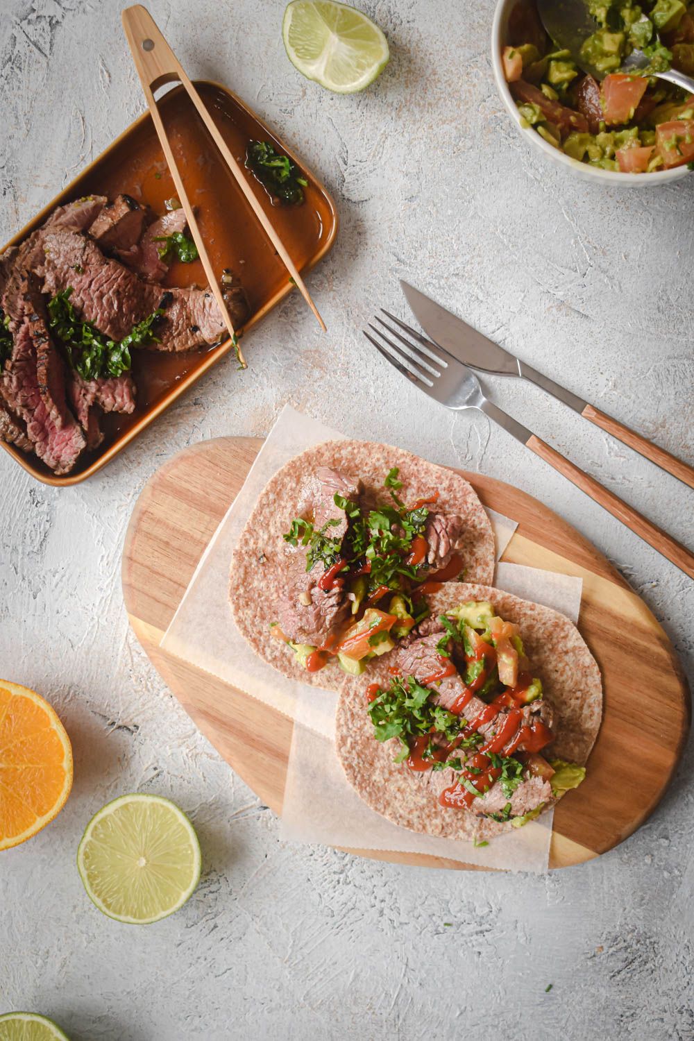 Mexican carne asada sliced on a plate and served in tortillas with guacamole.