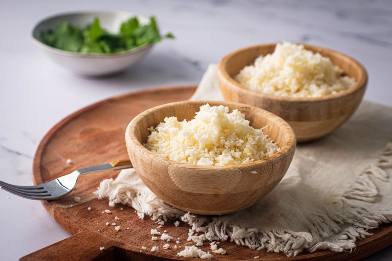 Low carb cauliflower rice with fresh cauliflower served with cilantro on the side.