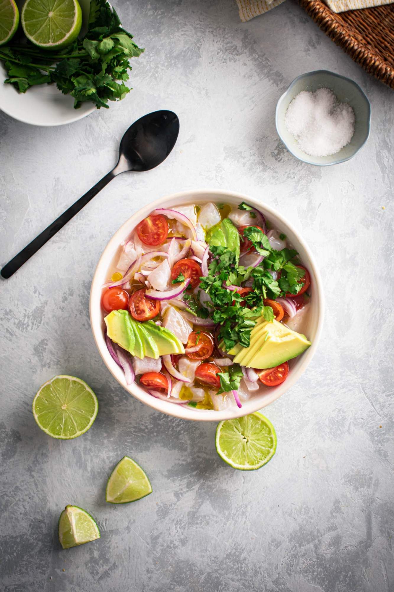 Marinated fish in lime juice to make ceviche with cilantro, red onions, cubed white fish, and avocado.