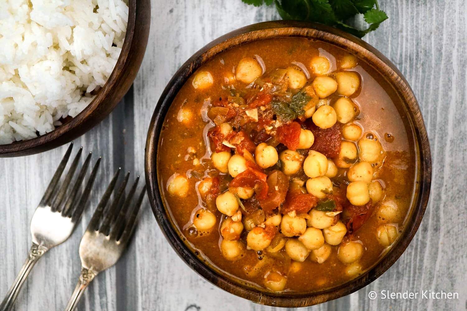 Chana masala with chickpeas in a bowl with tomato broth and white rice on the side.