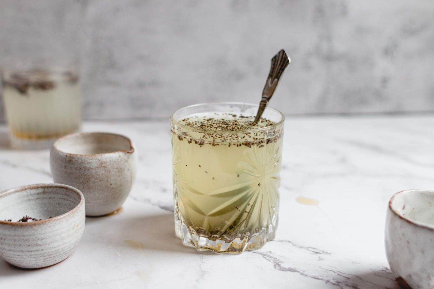 Chia lime water served in a glass with lime slices and a spoon.