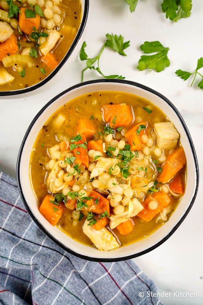 Sweet potato chicken soup in a bowl with a checkered napkin and parsley.