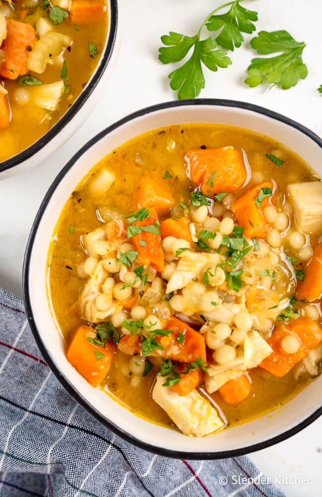 Chicken and sweet potato noodle soup with Israeli couscous, sweet potatoes, and parsley in a bowl.