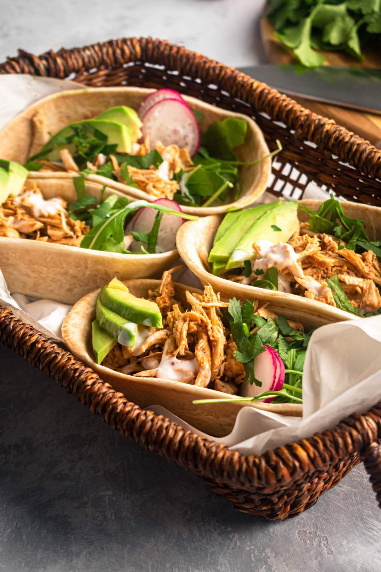 Barbcoa tacos made with chicken breast and served as tacos with cilantro, avocado, and radishes.