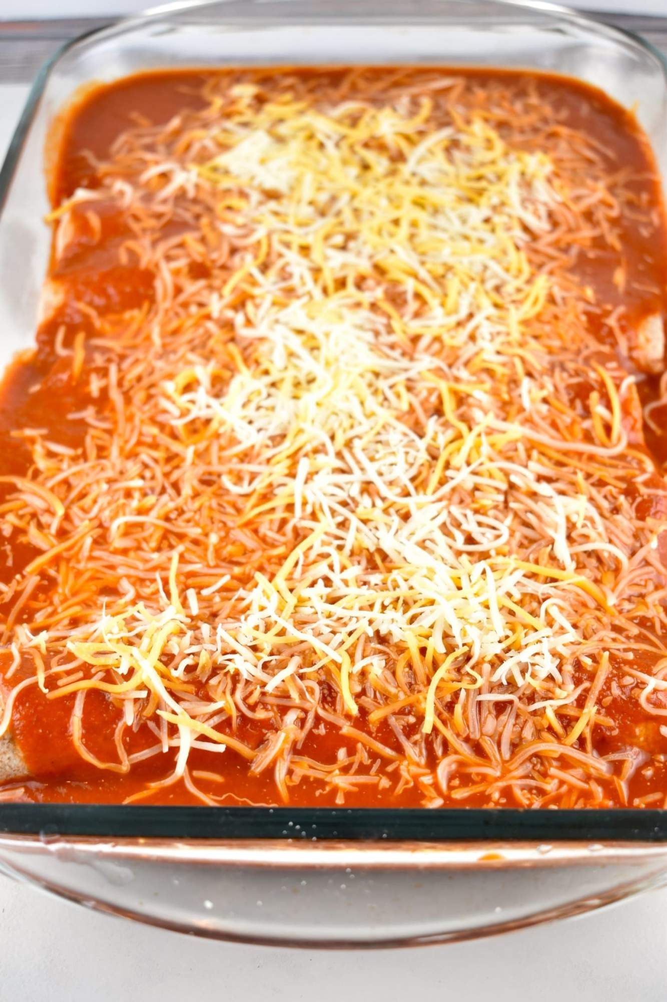 Chicken and black bean enchiladas in a glass baking dish before being cooked.