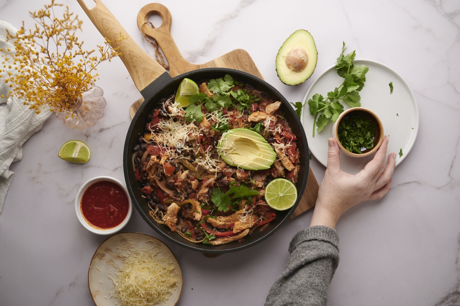 Burrito bowls with chicken, bell peppers, onions, black beans, and rice in a skillet.