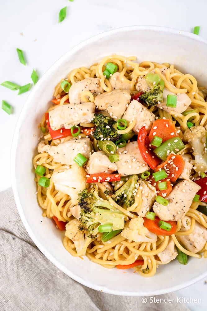 Chicken chow mein with broccoli, cauliflower, chicken, carrots, and green onions in a bowl with chopsticks.